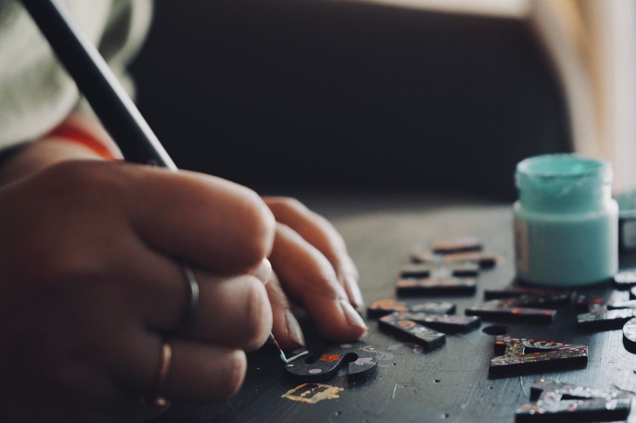 The Art of Drawing Readers In: Your attractive post title goes here Detailed view of a hand using a brush to paint puzzle pieces, showcasing artistic creativity and precision.
